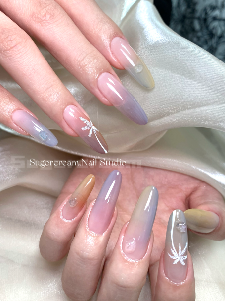 Luxurious long nails featuring a gradient design and floral accents in soft pastel colours.