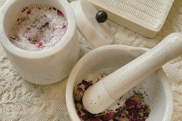 Mortar and pestle with crushed herbs and pink salt, beside a small lidded container.