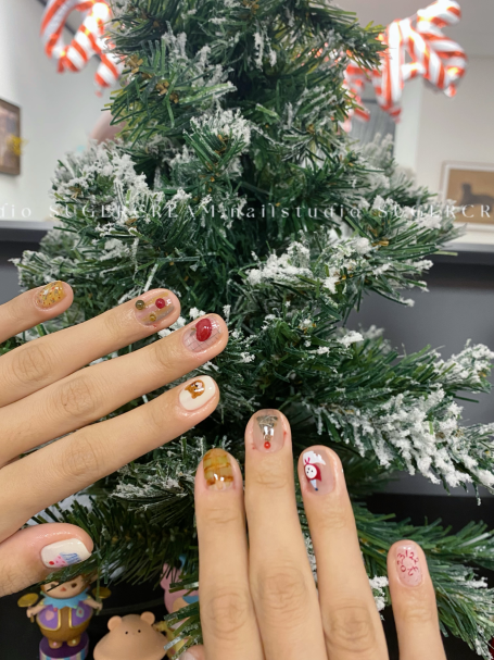 Festively decorated hands showing colourful nail art in front of a Christmas tree.