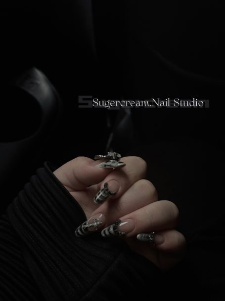 A hand with long, stylish nails, holding a cigarette in a dimly lit setting.