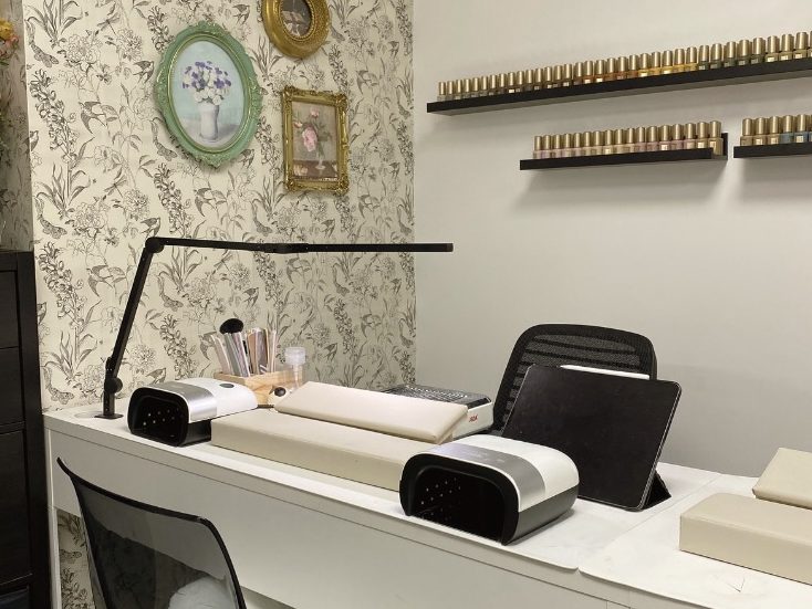 A neatly arranged salon workspace with a desk, chair, and decorative wall.