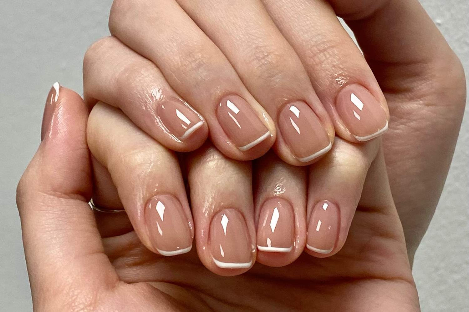 Close-up of hands with manicured nails in soft, neutral shades and iridescent accents.