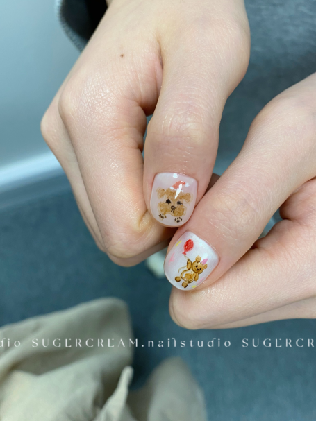 Close-up of hands with nail art featuring floral designs and a heart on a white base.
