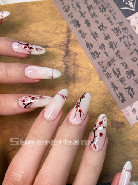 Nail art featuring elegant pink and white designs with red floral accents and pointed tips.