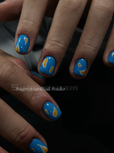 Blue nails with orange abstract designs on fingers.