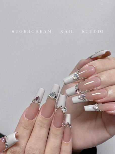 Elegant long nails featuring a mix of white tips and silver embellishments.