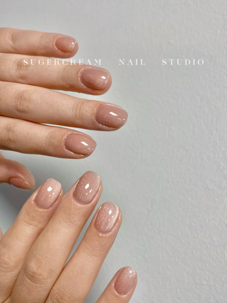 Close-up of two hands with neatly manicured, nude nail polish.