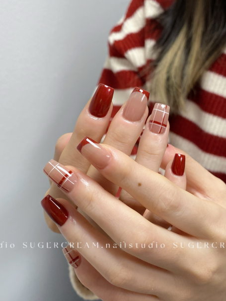 Fashionable manicure featuring red and nude nails with intricate patterns and designs.