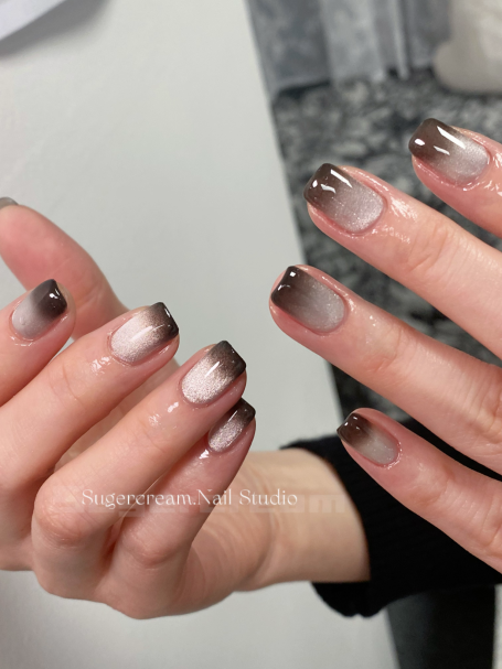 Hands displaying manicured nails with a gradient ombre effect in neutral shades.