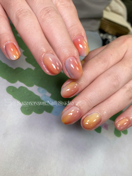 Hands with multicoloured gradient nail polish in shades of orange, pink, and purple.