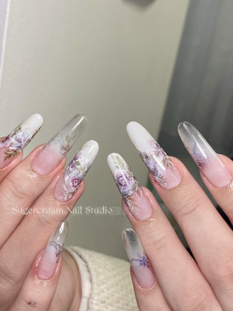 Long, elegantly manicured nails with floral designs and a ombre effect.
