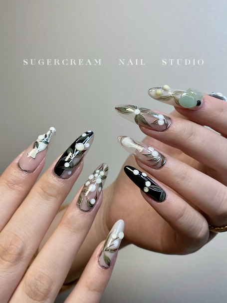 Long, stylish nails featuring black, white, and grey patterns with decorative beads.