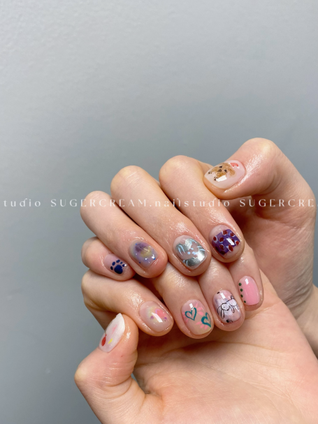 Colourful manicured nails with various designs displayed on both hands.