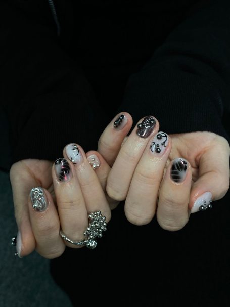 Stylish black and white manicured nails with various designs on both hands.